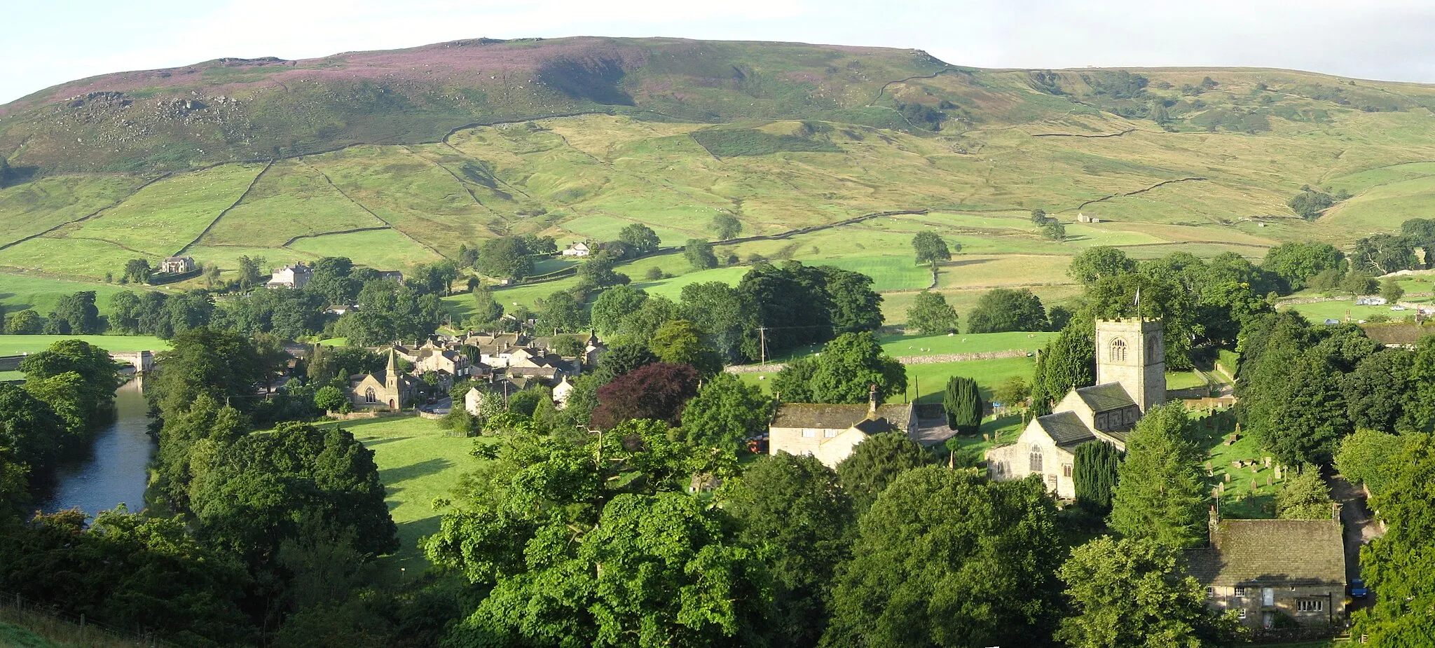 Photo showing: View of Burnsall, Yorkshire from west height, showing Wharfe, bridge, town, chapel, church, Burnsall Fell behind--late summer.