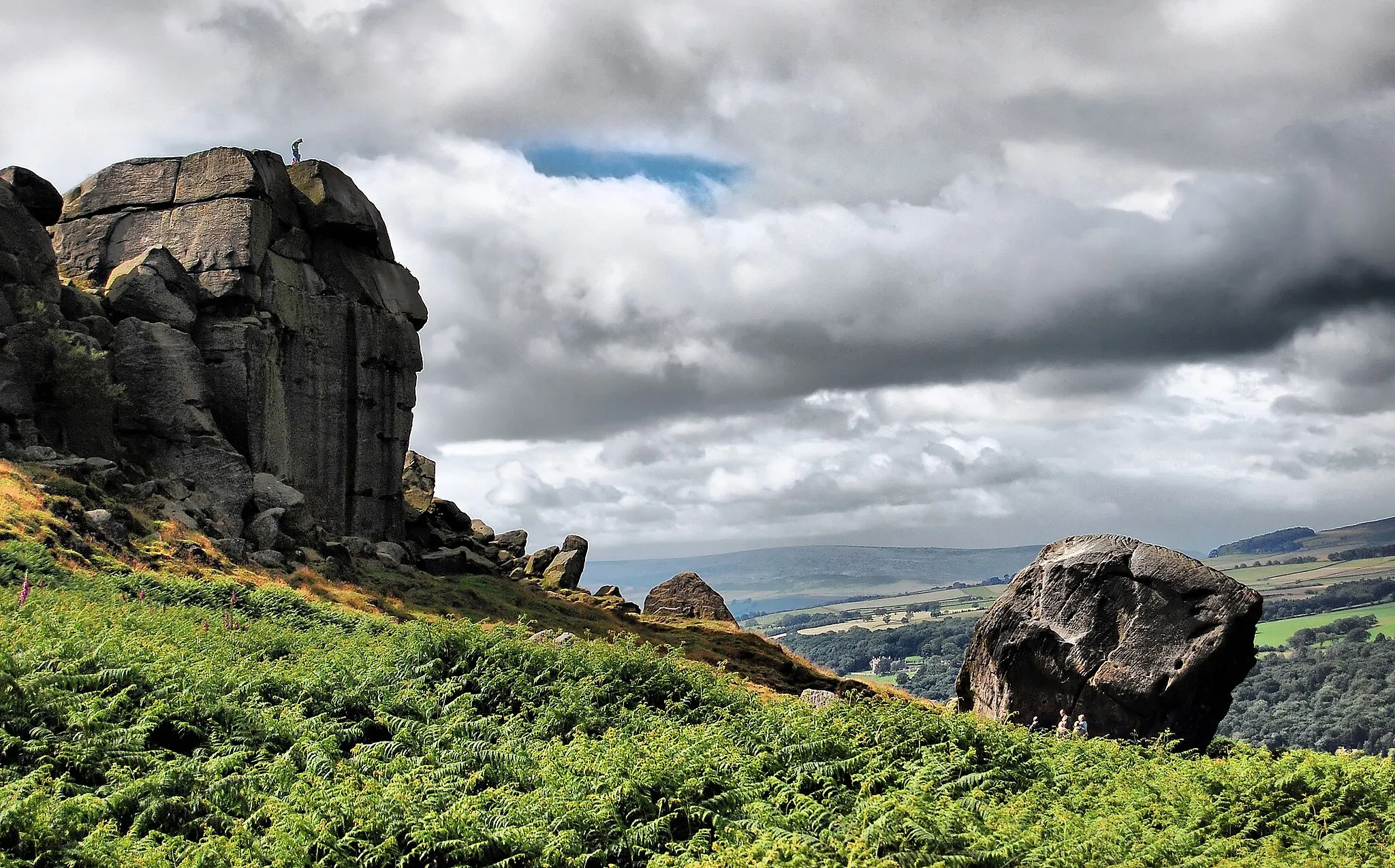Photo showing: The Cow and Calf rocks above Ilkley.
The smaller rock, or "calf", is estimated to weigh about a thousand tonnes and to have fallen away from the rock face at some point in the last 10,000 years. Geologists suggest its movement was arrested from going further downhill by the Wharfedale ice stream, which had by then sunk to the level at which the boulder now rests.